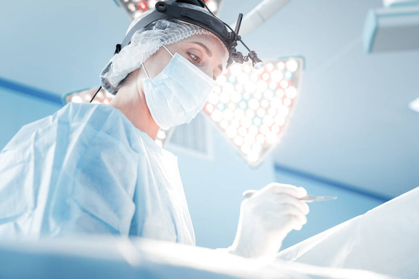 Professional skilled surgeon looking at her patient - Valokuva, kuva