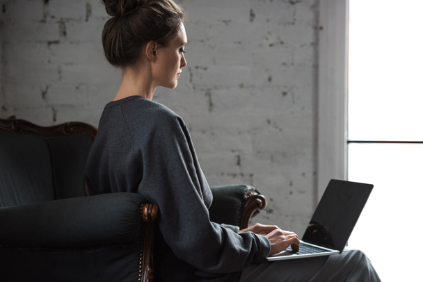 side view of beautiful brunette woman using laptop with blank screen - Fotoğraf, Görsel