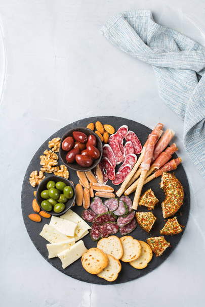 Still life, food and drink, holidays concept. Assortment of spanish tapas or italian antipasti with meat, ham, olives, cheese, nuts and bread on a table. Top view flat lay background - Photo, Image