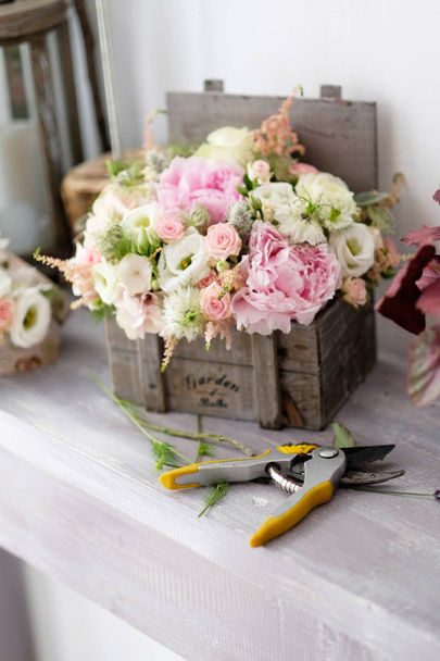 Buquê de rosas decorativas na mesa dentro da loja de flores. Arranjo de buquê de rosas bonitas para eventos especiais em uma caixa de madeira vintage
. - Foto, Imagem