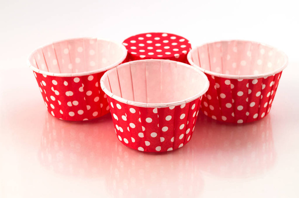 Four round paper forms for homemade baking red cakes in white peas, one form is turned upside down. - Photo, Image