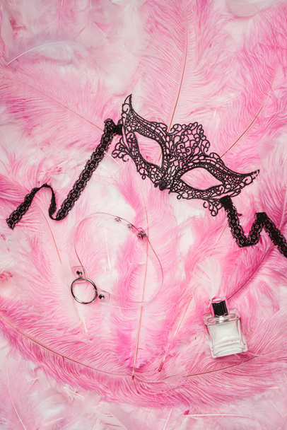 Masque noir avec collier et parfum sur plumes roses
 - Photo, image