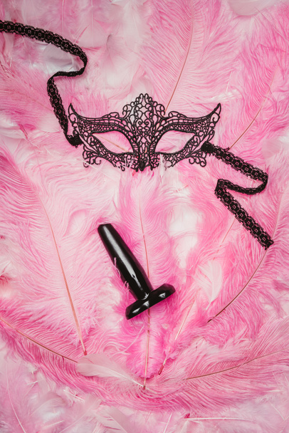 Butt plug and black mask on pink feathers - Φωτογραφία, εικόνα