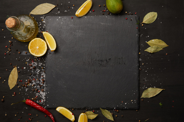 Доска темная со специями и ломтиками лимона
 - Фото, изображение