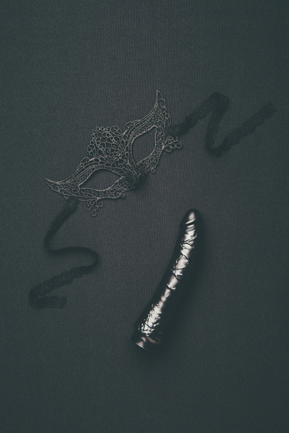 Black dildo and lacy mask isolated on black - Photo, Image