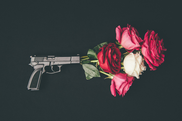 Fusillade avec bouquet de fleurs roses isolées sur noir
 - Photo, image