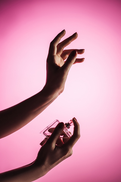 cropped view of sensual woman spraying perfume on hand, isolated on pink - Foto, afbeelding