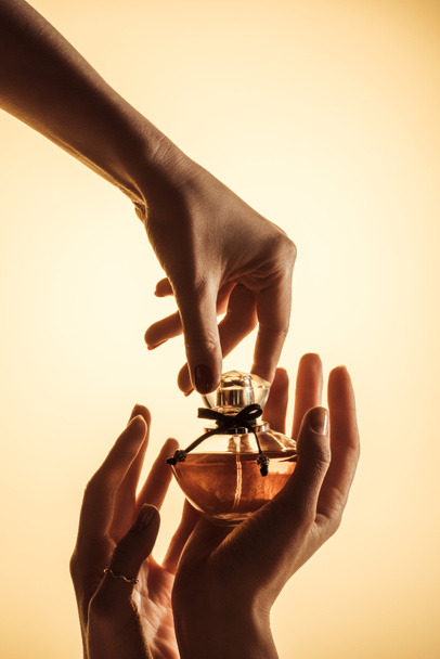 oříznutý pohled ženských rukou s parfémy láhev, izolované na žluté - Fotografie, Obrázek