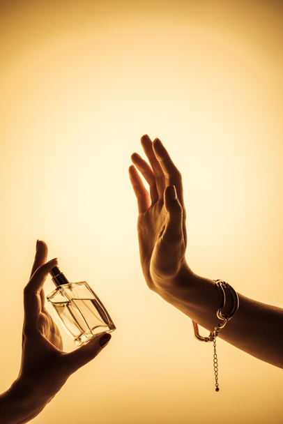 女性は黄色の分離の香りを感じるために手に香水をスプレーのトリミング ビュー - 写真・画像