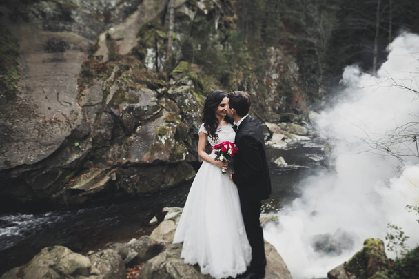 Kissing wedding couple staying over beautiful landscape - Fotografie, Obrázek