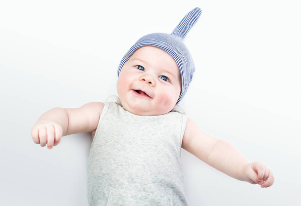 Funny baby in a cap on a light background. A handsome little boy with blue eyes - Fotografie, Obrázek