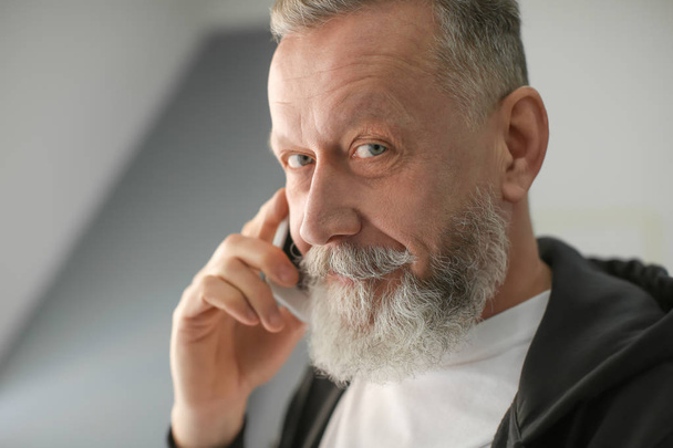 Senior man praten op mobiele telefoon op werkplek op kantoor - Foto, afbeelding