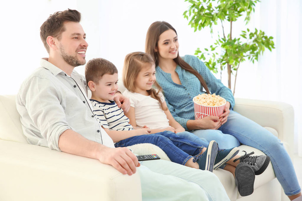 Family watching TV on sofa at home - Fotó, kép