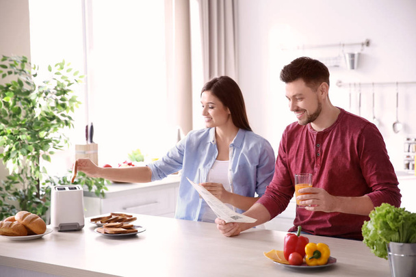 Young couple having breakfast with toasts in kitchen - Foto, Bild