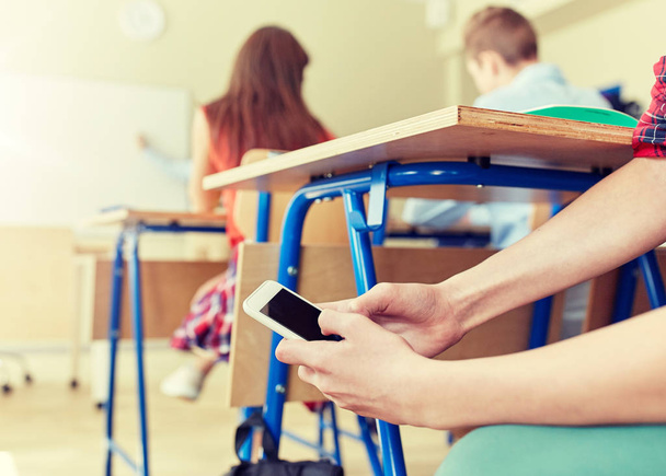 student boy with smartphone texting at school - Foto, Bild