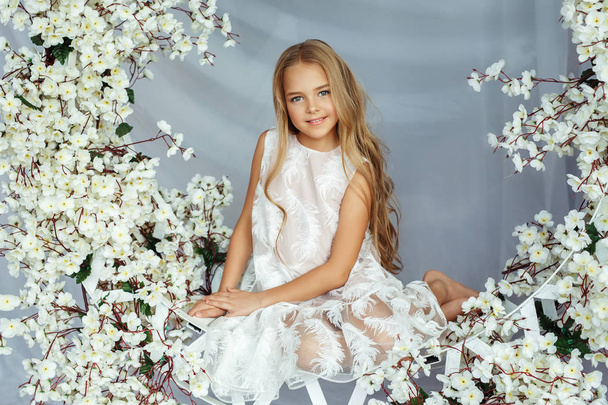 elegant little girl sitting in floral swing - Fotoğraf, Görsel