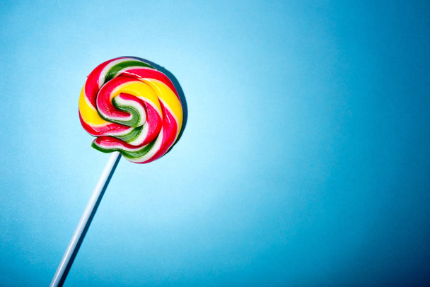 Kolorowe spirali candy lollipop na kij. Na niebieskim tle. - Zdjęcie, obraz