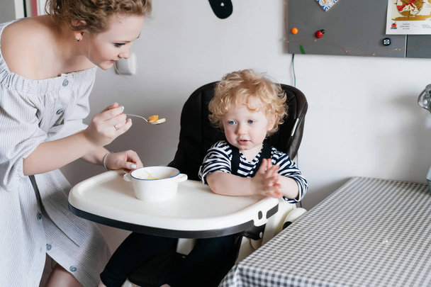 beautiful mother feeds her young son, spend time together in the kitchen - Photo, Image