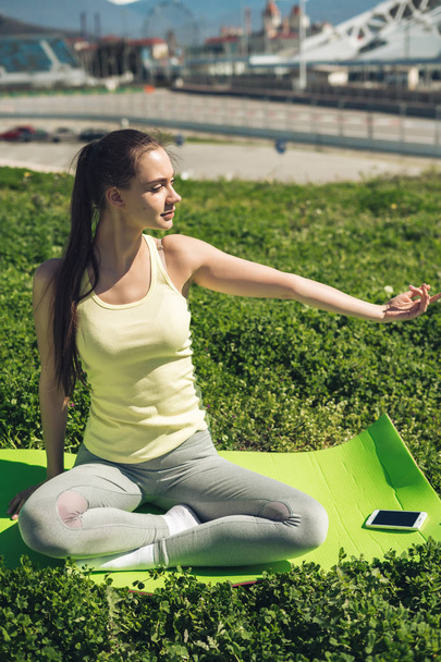 a young girl leads a healthy lifestyle, practicing yoga on green grass, spring weather and sports - Foto, imagen