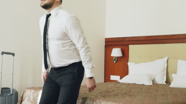 Slow motion of Happy businessman jumping on bed at hotel room and lying relaxed smiling. Business, travel and people concept - Video