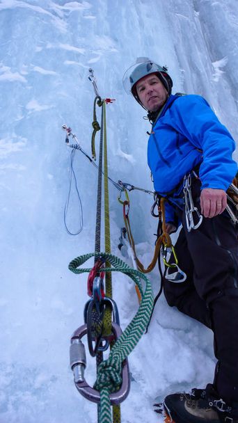 escalador de gelo macho em uma posição de atraso em uma queda de gelo íngreme nos Alpes
 - Foto, Imagem