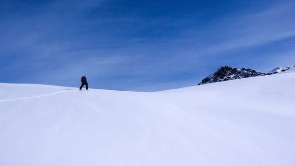 サンモリッツ周辺のアルプスの美しい冬の日に山に登る男性バックカントリー スキーヤー - 写真・画像