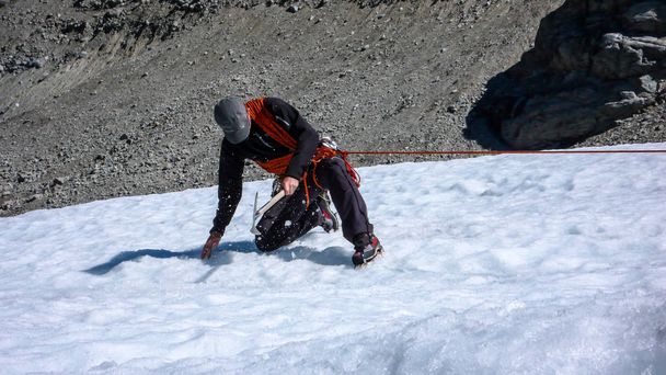ένας οδηγός αρσενικό βουνό την εγκατάσταση ένα σύστημα τροχαλιών για διάσωση του crevasse σε έναν παγετώνα - Φωτογραφία, εικόνα