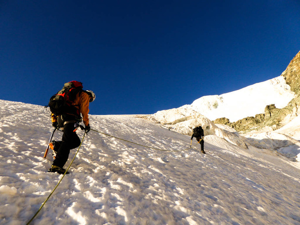 οδηγός βουνού και πελάτη κλάση επάνω έναν παγετώνα προς μια υψηλή αλπικό σύνοδο κορυφής σε μια όμορφη το πρωί το καλοκαίρι - Φωτογραφία, εικόνα