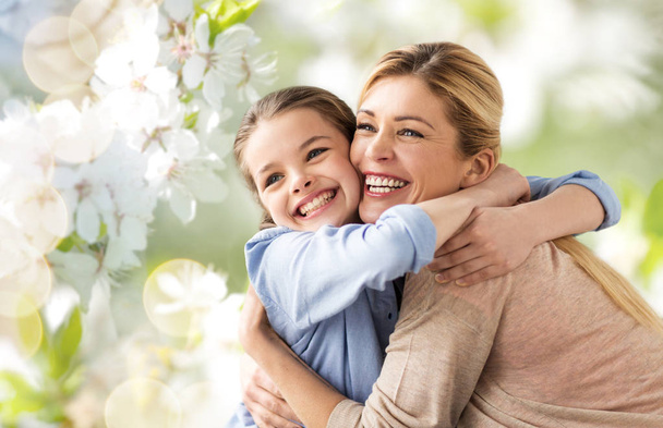 happy mother hugging daughter over cherry blossom - Zdjęcie, obraz