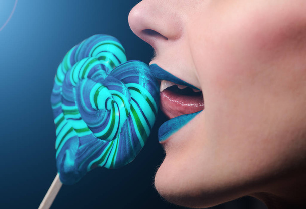 emotional girl with a lollipop over black background - Fotó, kép