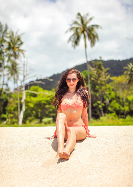 Young woman in red bikini sitting on the fine sand beach with pa - Foto, immagini