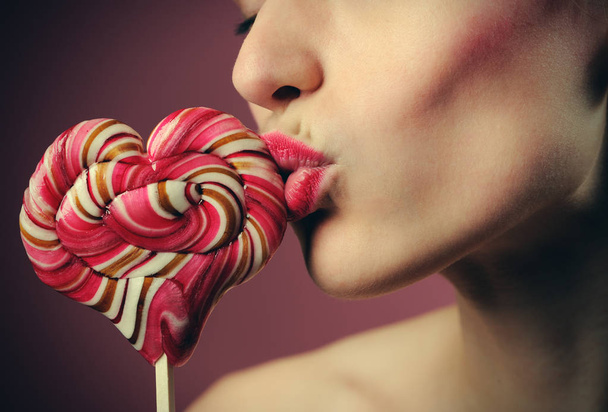 emotional girl with a lollipop over pink background - Photo, Image