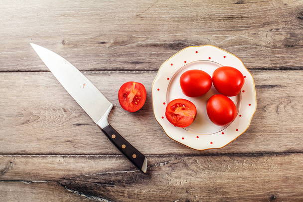Tabletop photo of tomatoes, one of them cut, on a plate, with ch - Foto, Bild
