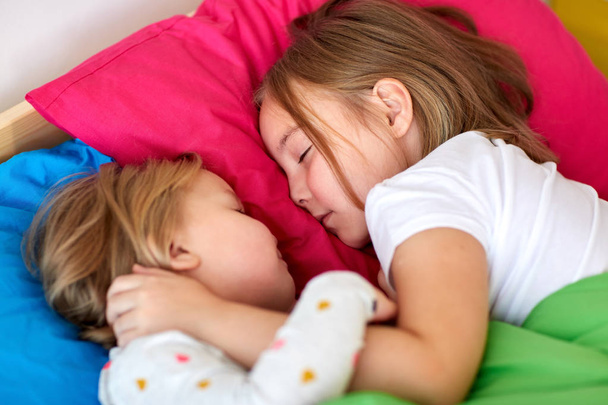 happy little girls sleeping in bed at home - Foto, afbeelding