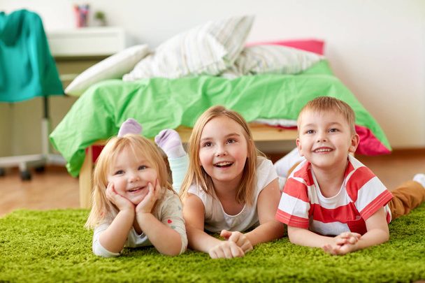 glückliche kleine Kinder, die auf dem Boden oder Teppich liegen - Foto, Bild
