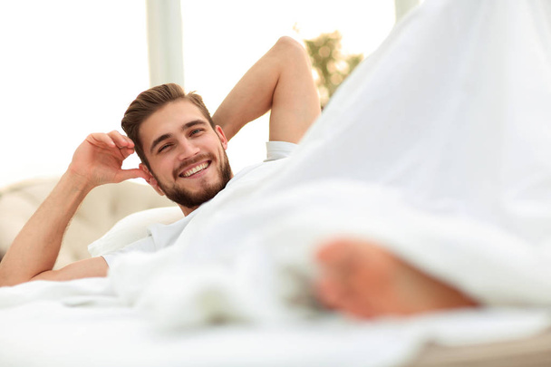 closeup.smiling man resting in the bedroom - Фото, изображение
