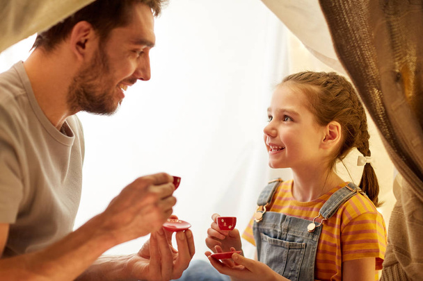 family playing tea party in kids tent at home - 写真・画像