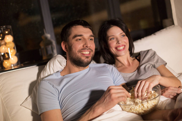 couple with popcorn watching tv at night at home - Foto, Bild