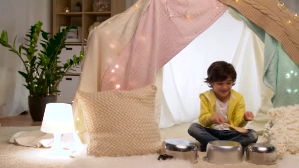 boy with pots playing music in kids tent at home - Footage, Video
