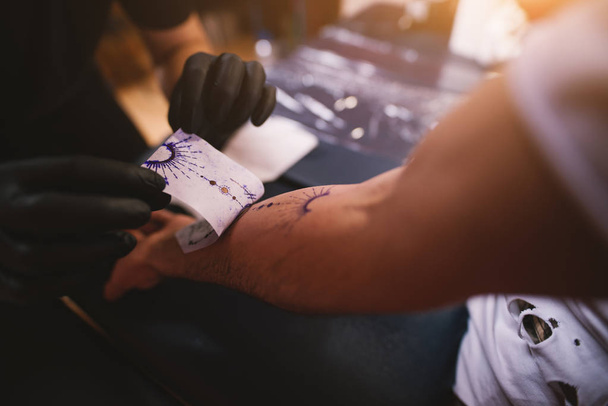 joven profesional tatuaje maestro la eliminación de boceto del brazo del cliente
 - Foto, imagen