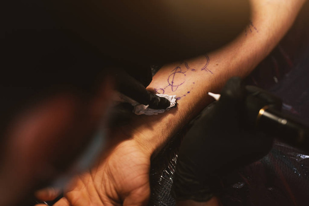 young focused tattoo artist inking arm of customer - Zdjęcie, obraz