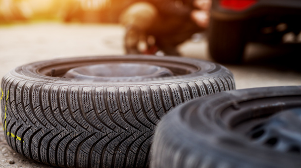neumáticos nuevos en el pavimento cerca del coche en el garaje
 - Foto, Imagen