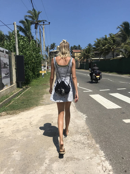 Woman walking on the street in a tropical country. - Фото, изображение