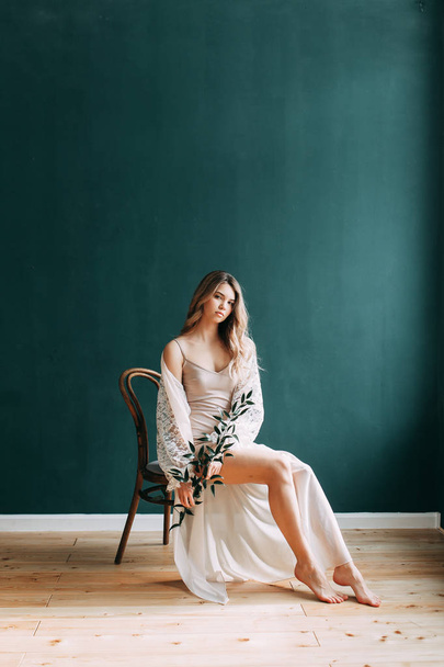 Young beautiful bride in boudoir and wedding dress, with a wreath and a bouquet in her hands. London wedding trends, stylish photoshoot - Fotoğraf, Görsel