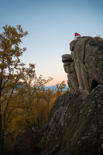 Widok z tyłu młody człowiek robi parkour, stojąc na rock i patrząc na krajobraz zachód słońca światła. - Zdjęcie, obraz