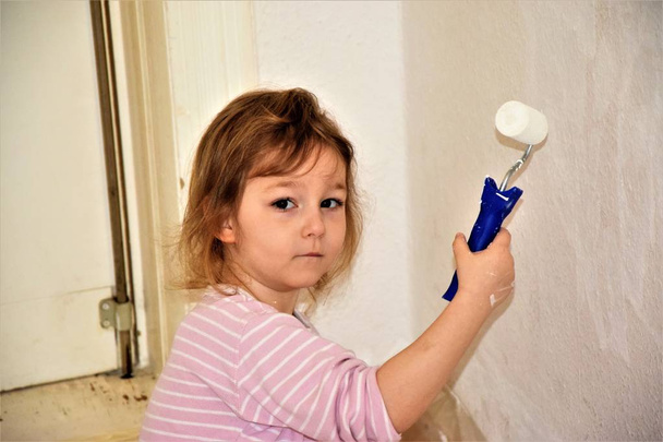 Девушка рисует стену на белом с роликом для покраски стен. Маленькая девочка-художник
 - Фото, изображение