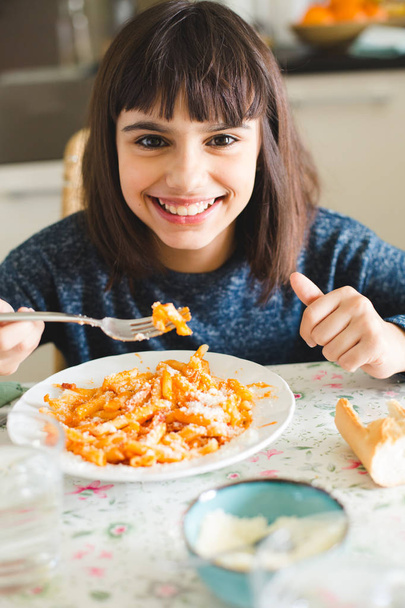 Happy little girl eating macaroni - 写真・画像