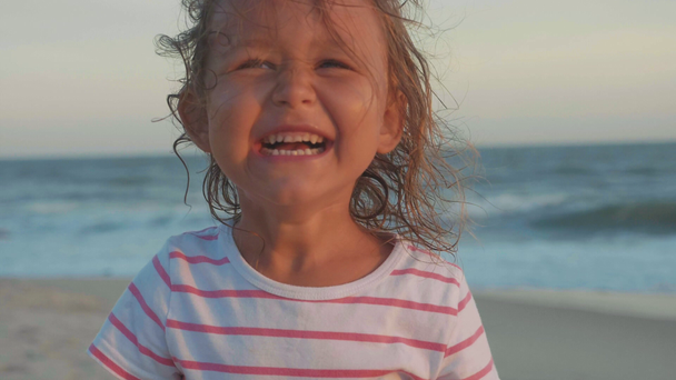 Portret van gelukkig kind meisje camera kijken en lachen om strand - Video