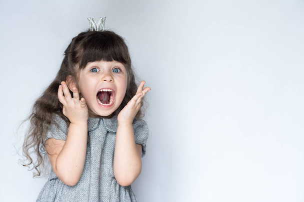 Portrait of 4-5 years old girl, screaming with open mouth and crazy expression. Surprised or shocked face. Free space for advertisement. - Photo, Image