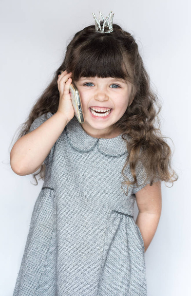 Nettes Mädchen, 4-5 Jahre alt, lacht und spricht mit einem Handy-Smartphone. isoliert auf weißem Hintergrund.  - Foto, Bild